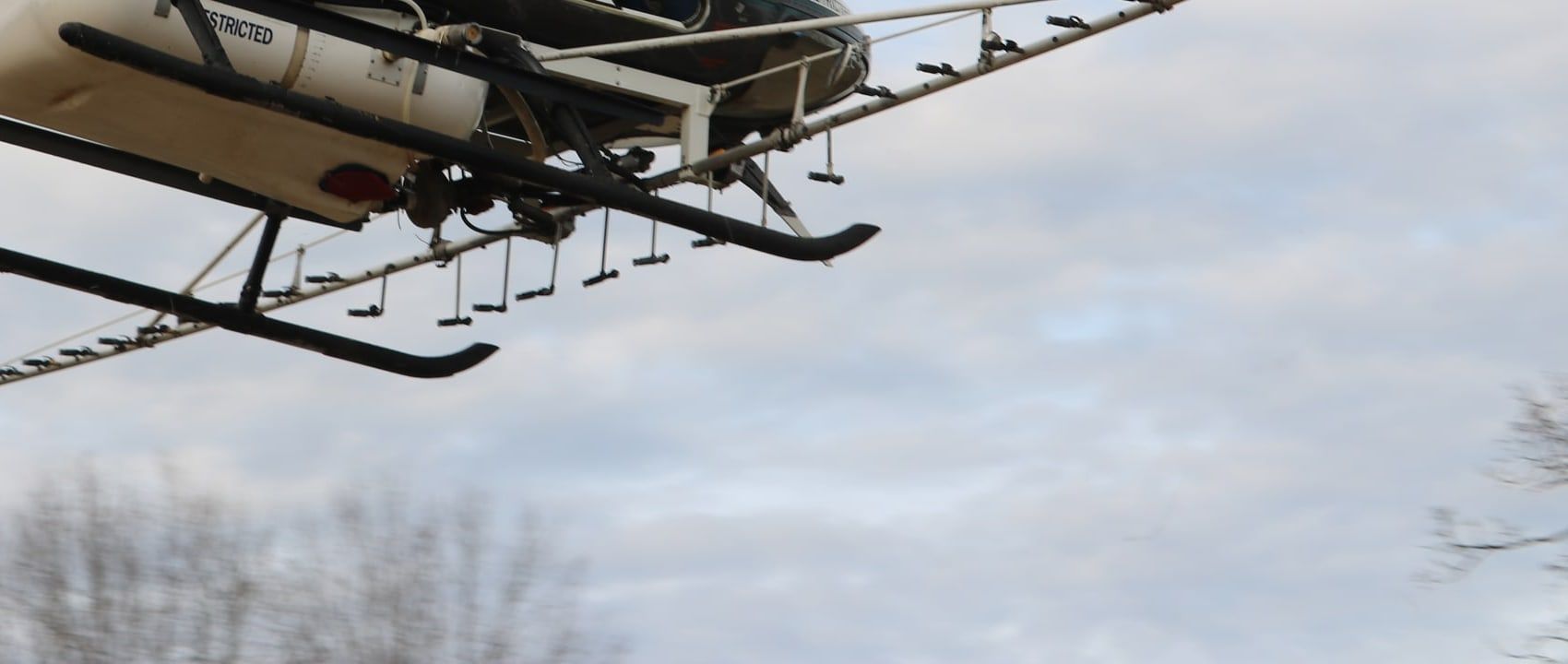 Spray booms, nozzles and the belly tank on the helicopter, seen from just below the skids